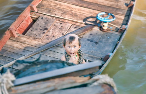 Boy with snake around neck floating village on Tonle Sap Lake