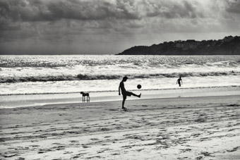 young man playing soccer on beach costa rica